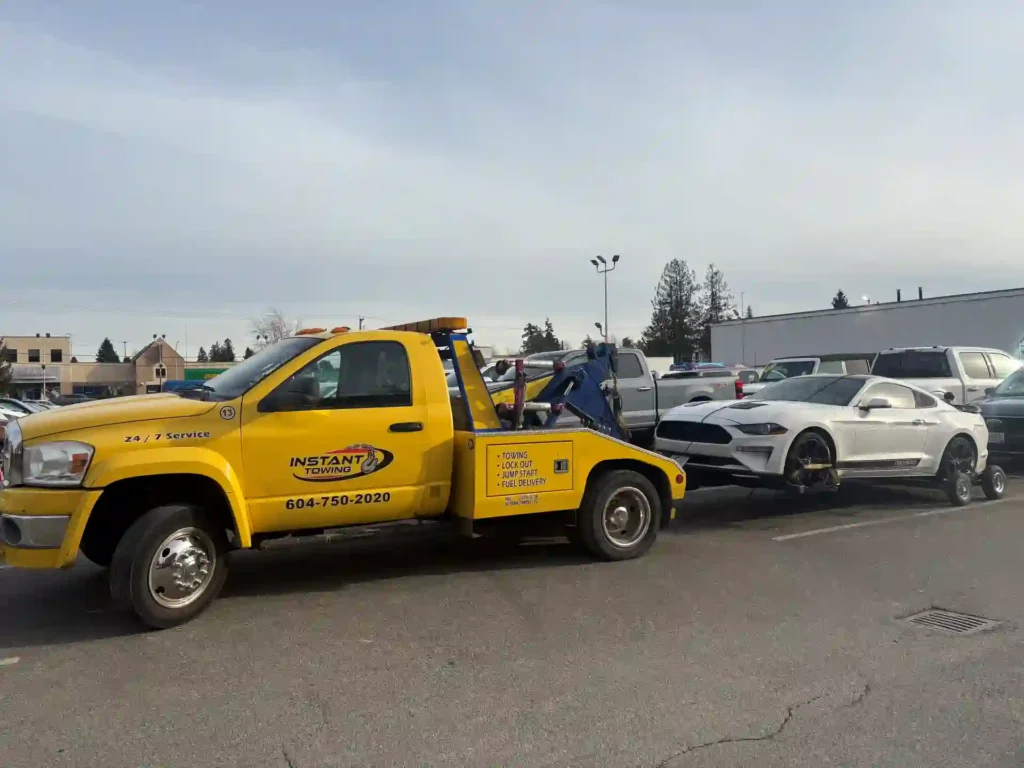 tow truck towing a white sedan car in surrey
